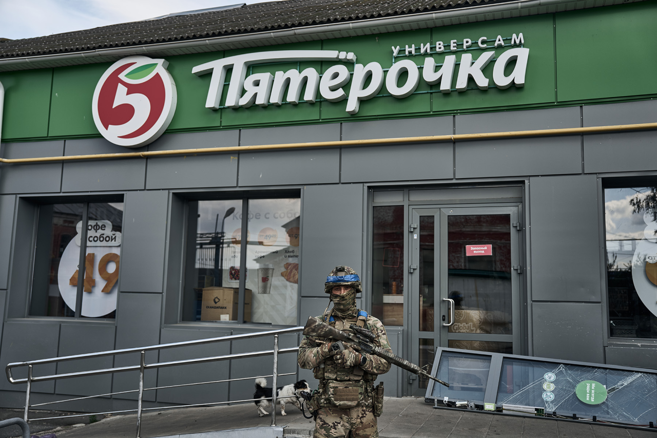 ПОПРАЦЮВАЛИ НА ПʼЯТІРОЧКУ: Український військовий позує на фоні магазину російської мережі універсамів (Фото: Kostiantyn Liberov / Libkos / Getty Images)