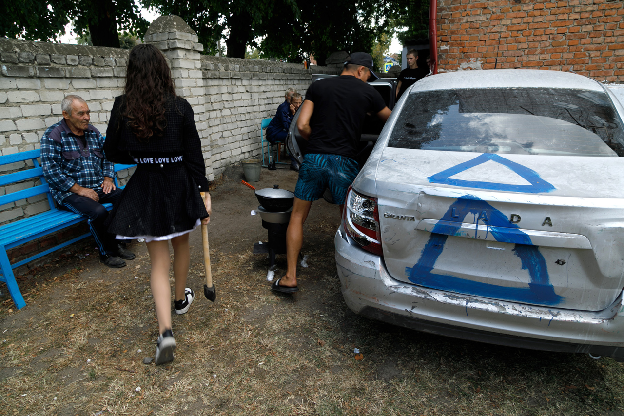 БЕЗПЕЧНЕ МІСЦЕ: Росіяни готують обід біля входу до шкільного підвалу, що перетворився на бомбосховище (Фото: Kirill Chubotin / Ukrinform / ABACA via Reuters)